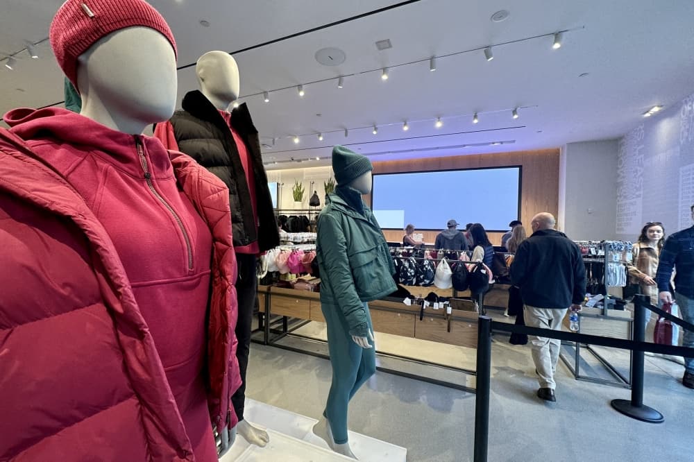Three mannequins in winter attire with cash registers and counters at the back.