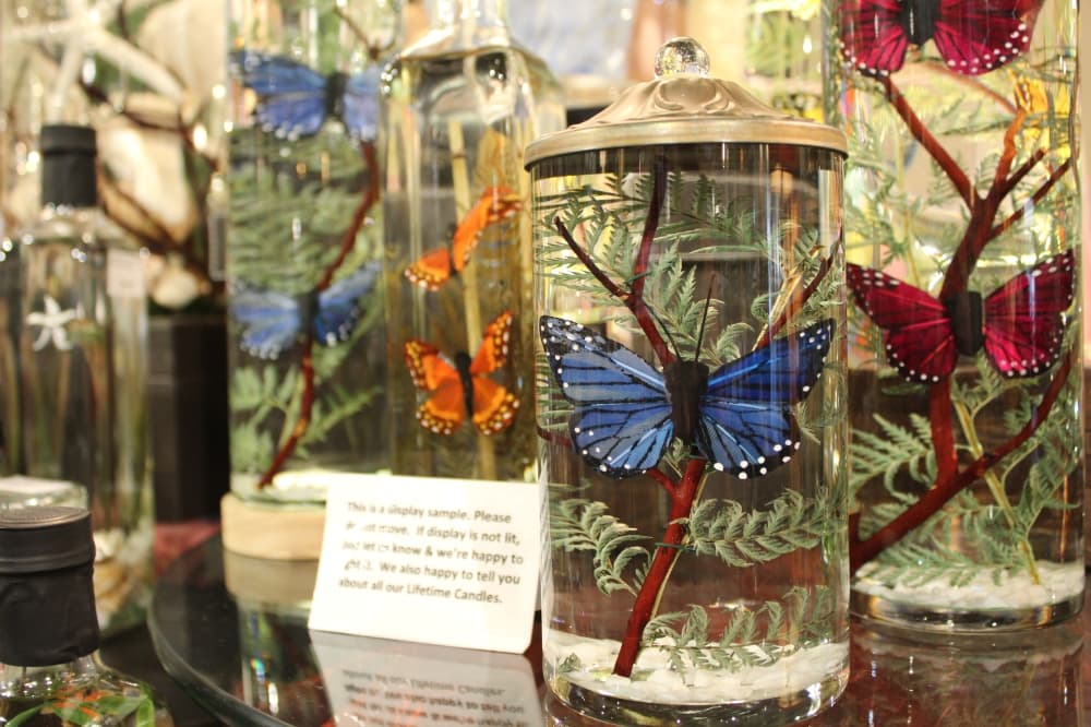 Candles with decorative butterflies are among the goods sold in the home decor area. 