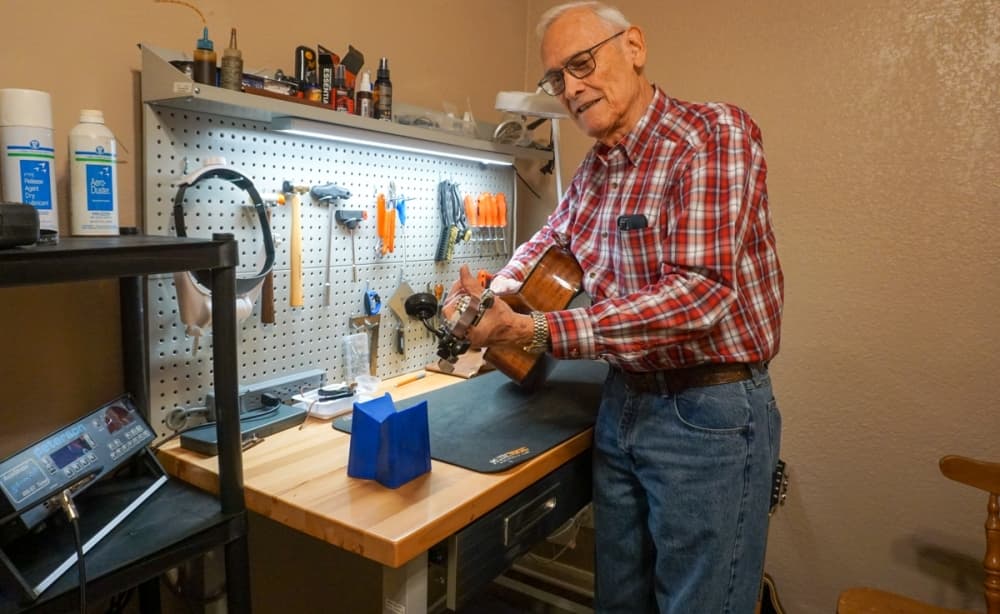 CW Guitars owner Chuck Woods checks the tone and tuning of a guitar on which he recently replaced the frets. (Sierra Martin/Community Impact)