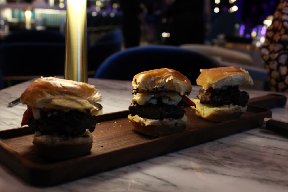 The wagyu sliders ($19) are served on brioche and topped with caramelized onions, roasted tomatoes, aged vintage cheddar and black garlic aioli. (Shelbie Hamilton/Community Impact)