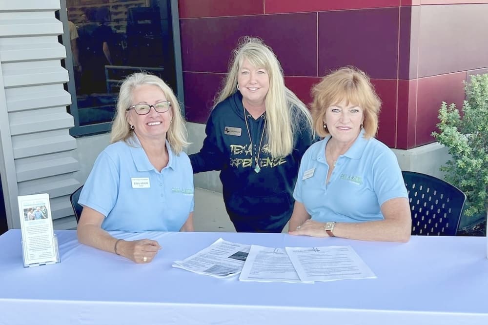 three woman sitting behind a table and smiling