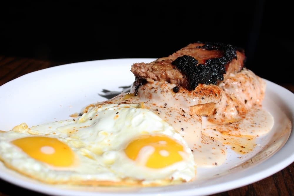 Brisket and biscuits ($14) comes with two homemade biscuits topped with gravy and brisket burnt ends. It is served with two eggs. (Karen Chaney/Community Impact)