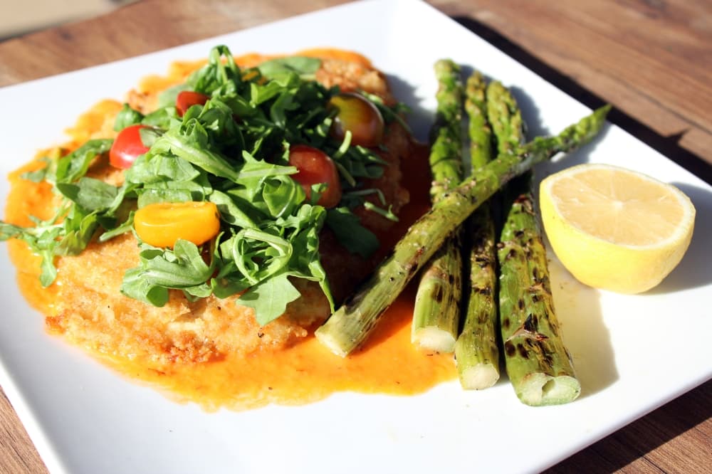 Chicken Milanese ($19) features chicken crusted with Panko and topped with arugula and citrus tomatoes. It is served with grilled asparagus. (Karen Chaney/Community Impact)