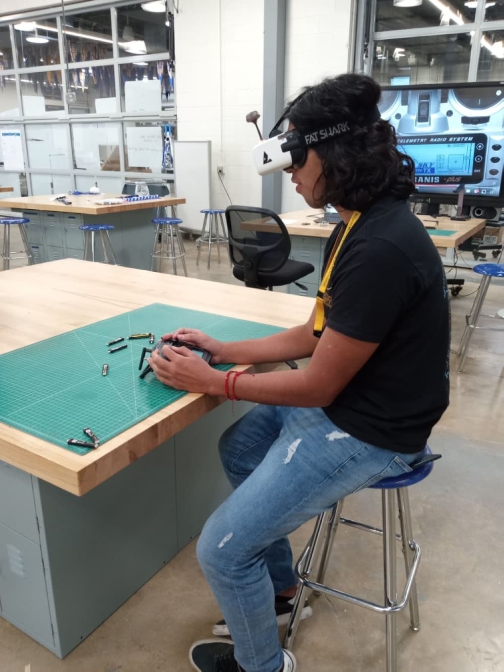 student sits at desk with high tech goggles using a first-person-view drone