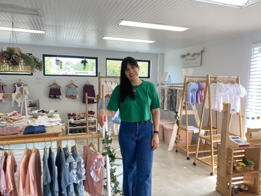 woman standing in shop with childrens clothes on all of the racks