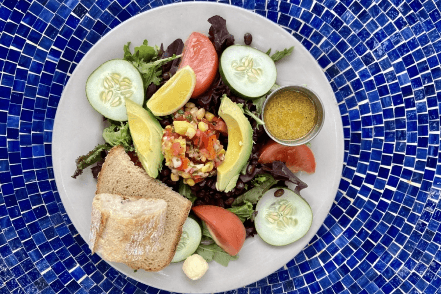 plated salad with avocado, tomato and cucumbers on a blue tile table 