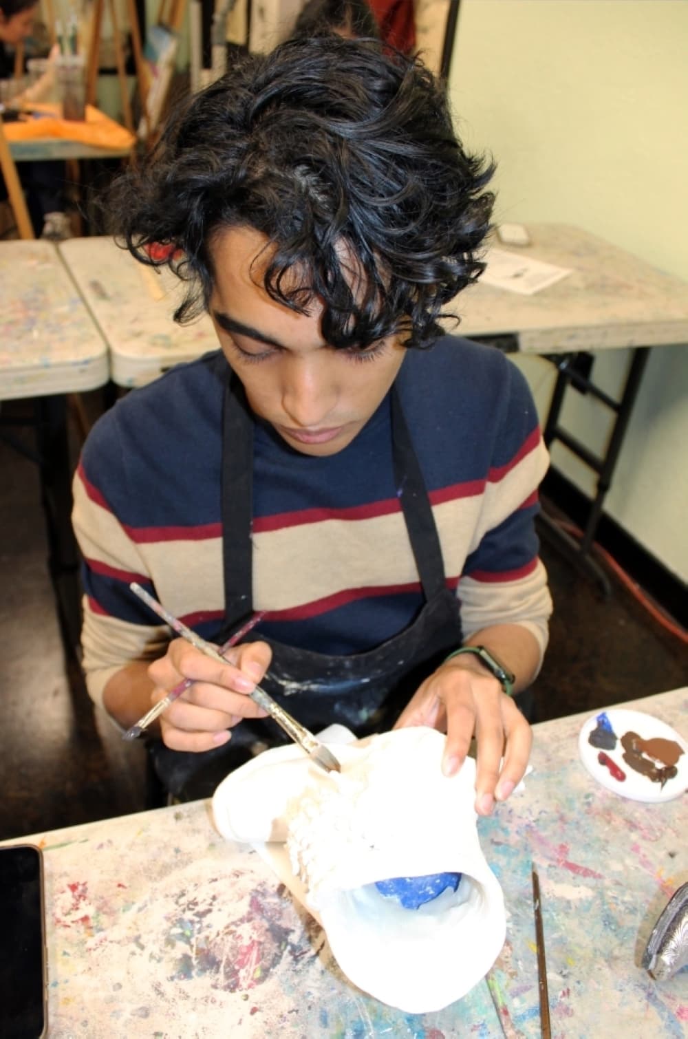 Joshua Thomas paints an air clay piece he created for the Ft. Worth Stock Show and Rodeo art contest. (Photo by Karen Chaney)