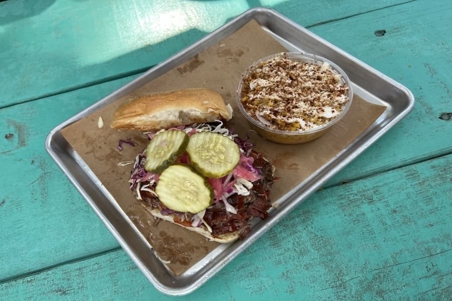 The Chopped Brisket Sando comes with a side of elote street corn at Louie's Craft BBQ. (Zacharia Washington/Community Impact)