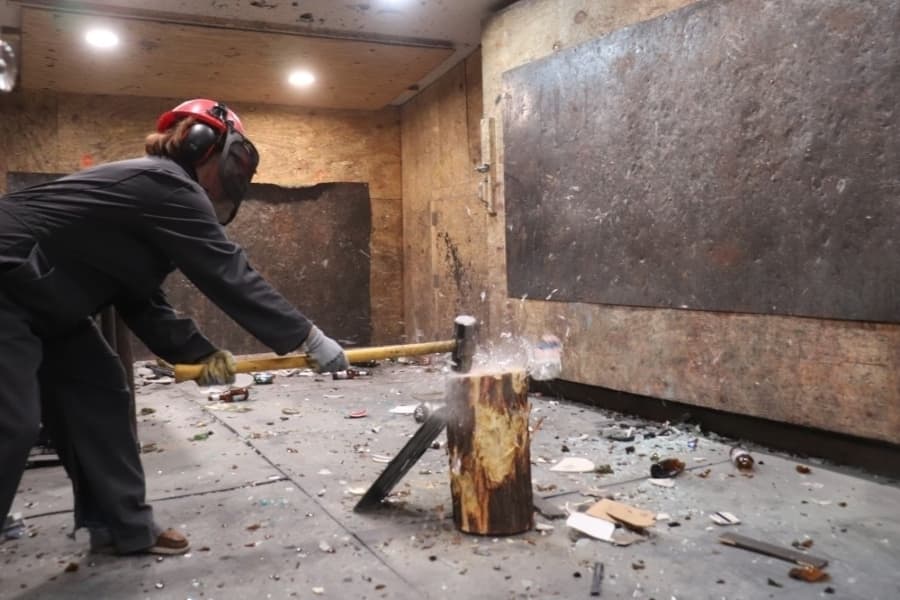 A patron smashes glassware in the rage room at Unchartered Adventures. (Zara Flores/Community Impact)