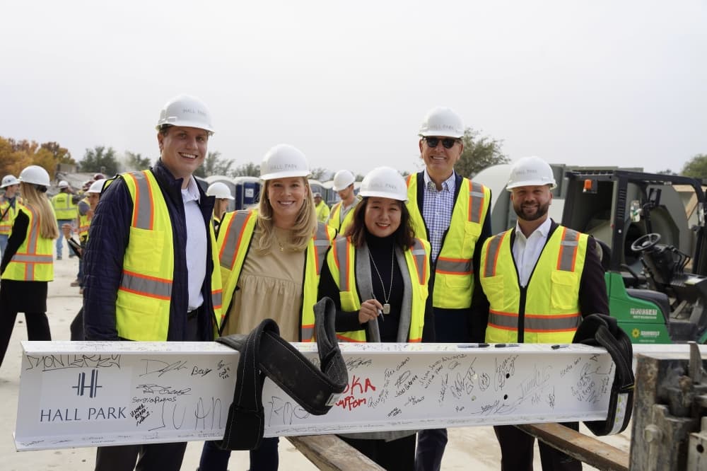 five people holding a signed beam