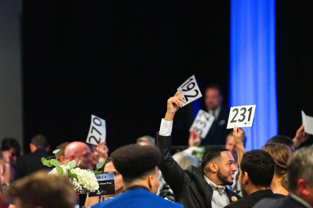 auction attendees wave their numbered cards in the air to place a bid