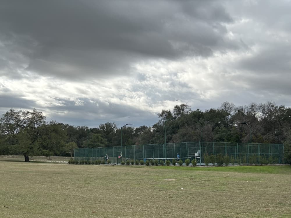 the tennis court at lake forest with trees behind it