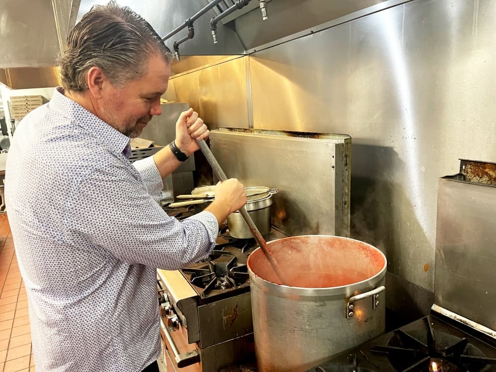 owner stirs red sauce in the kitchen 
