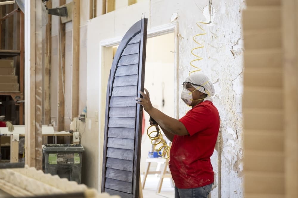 worker wearing construction mask and hair net works on brown shutter