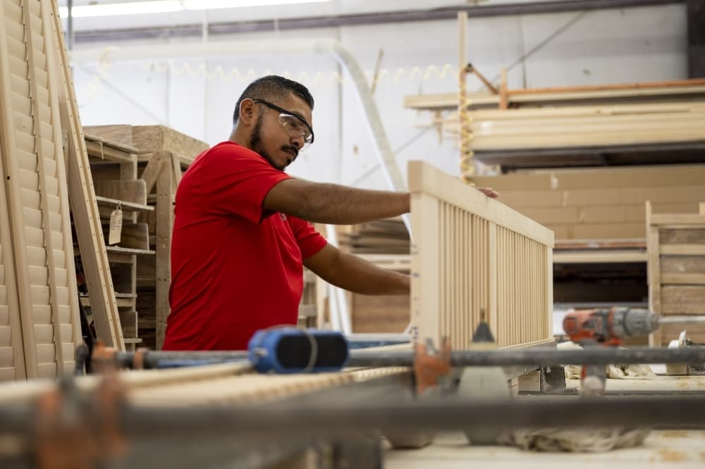 worker in red shirt works on wood shutter