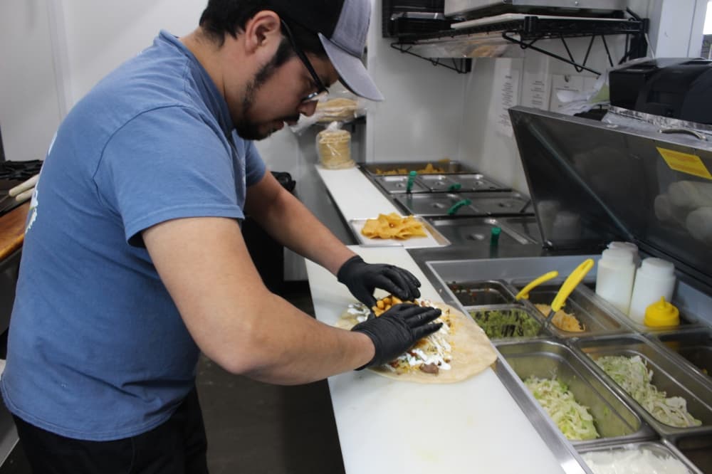 Co-owner and founder Miguel Camacho assembles the burrito at the grill. The majority of ingredients are made fresh every day in house. (Jessica Shorten/Community Impact)