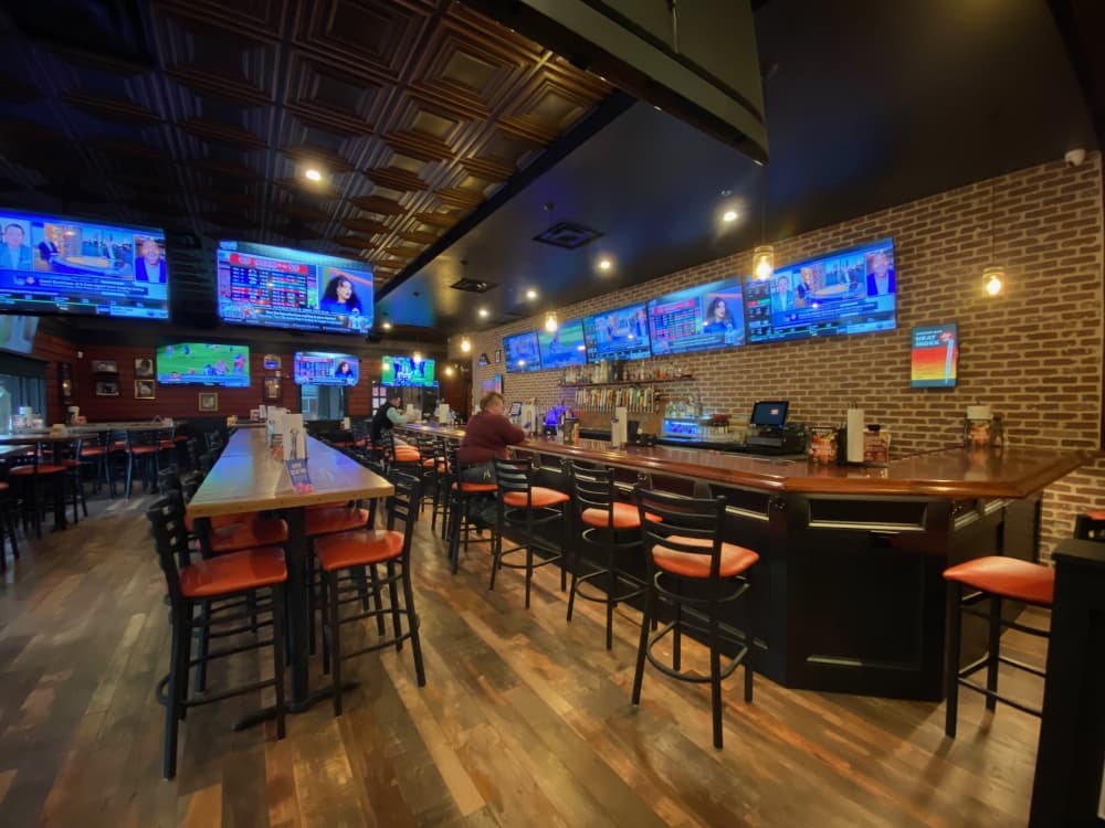interior of the restaurant has long tables with red barstools 