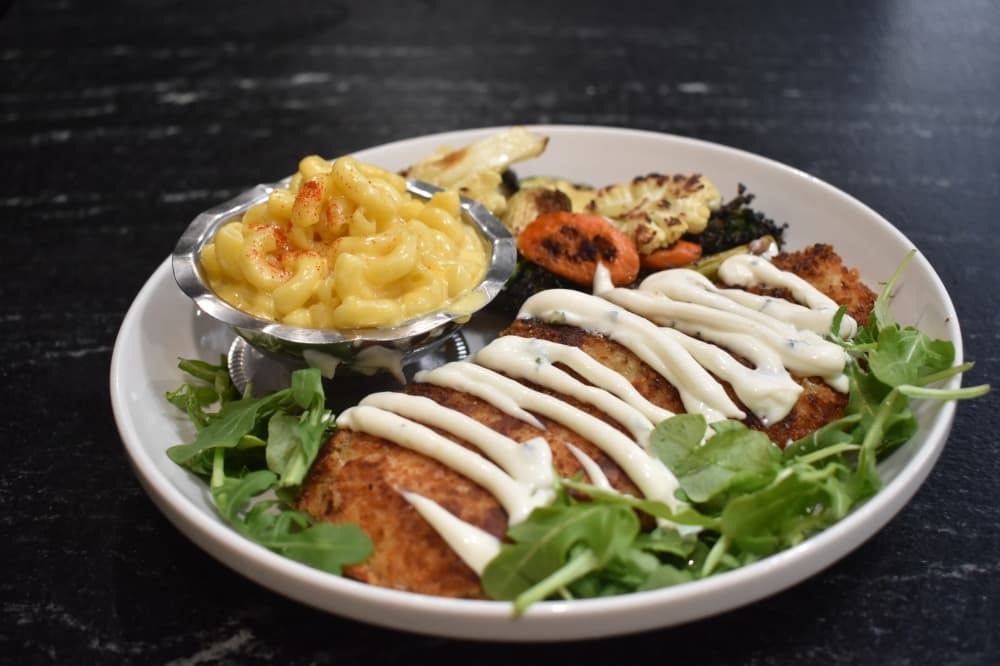 The pan-fried chicken dish comes with a panko and parmesan chicken breast over arugula with lemon garlic aioli, mac and cheese and roasted vegetables. (Lizzy Spangler/Community Impact)