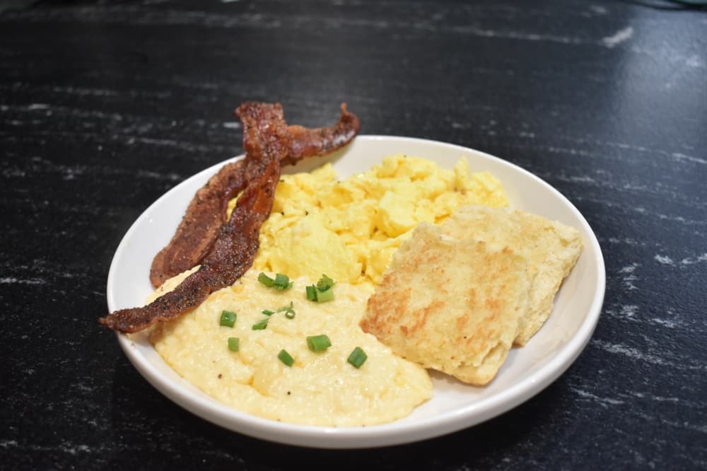 Heirloom Cafe and Market's classic breakfast plate comes with three eggs; bacon or sausage; biscuits or toast; and fruit salad or cheese grits. (Lizzy Spangler/Community Impact)