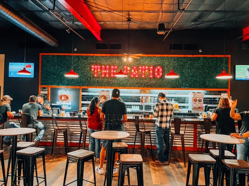interior of a bar with red lights, barstools and "the patio" written above the bar