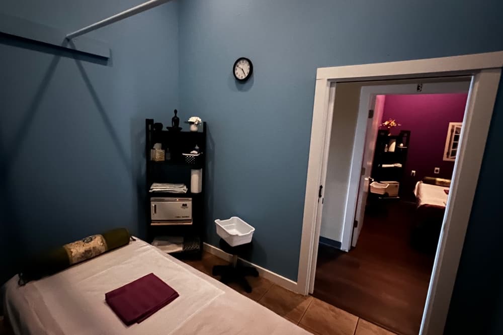 One massage bed in a room with door open 