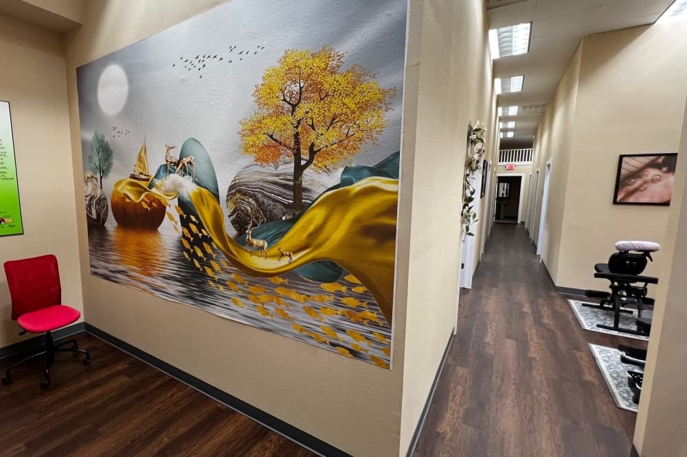 A wall sized painting with a tree, water and moon.