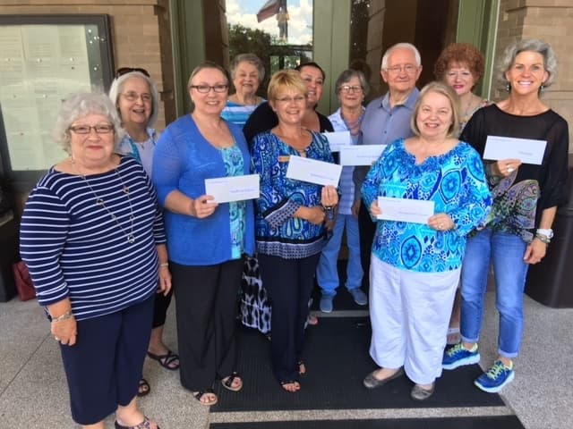 women wearing blue stand for photo holding envelopes
