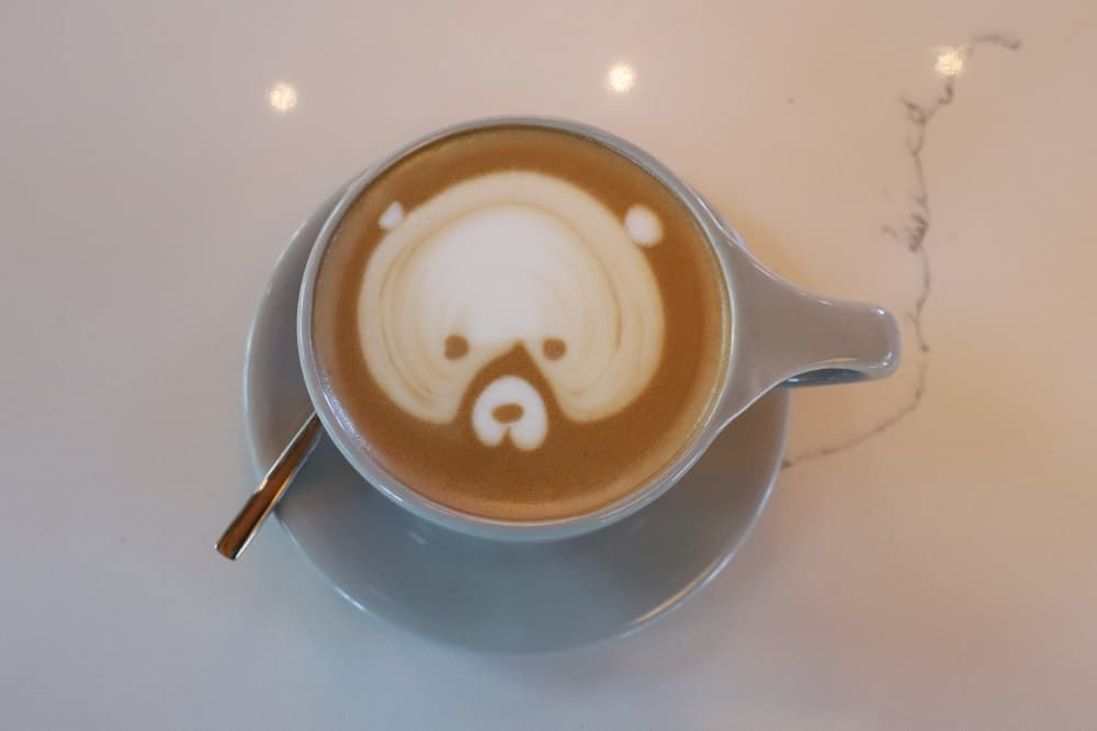 A mocha latte with foam art that looks like a teddy bear face. 