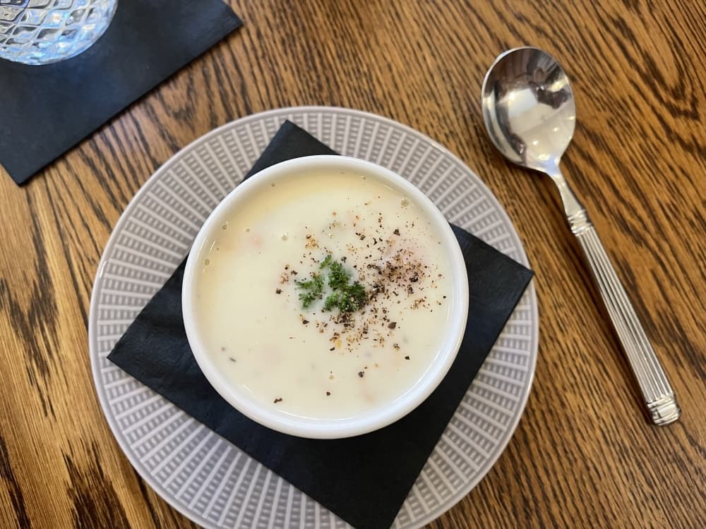clam chowder in a bowl on a plate with silver spoon 