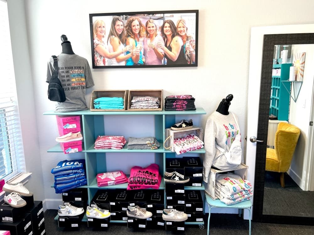 shelving at the store is filled with tshirts of different colors and sneakers