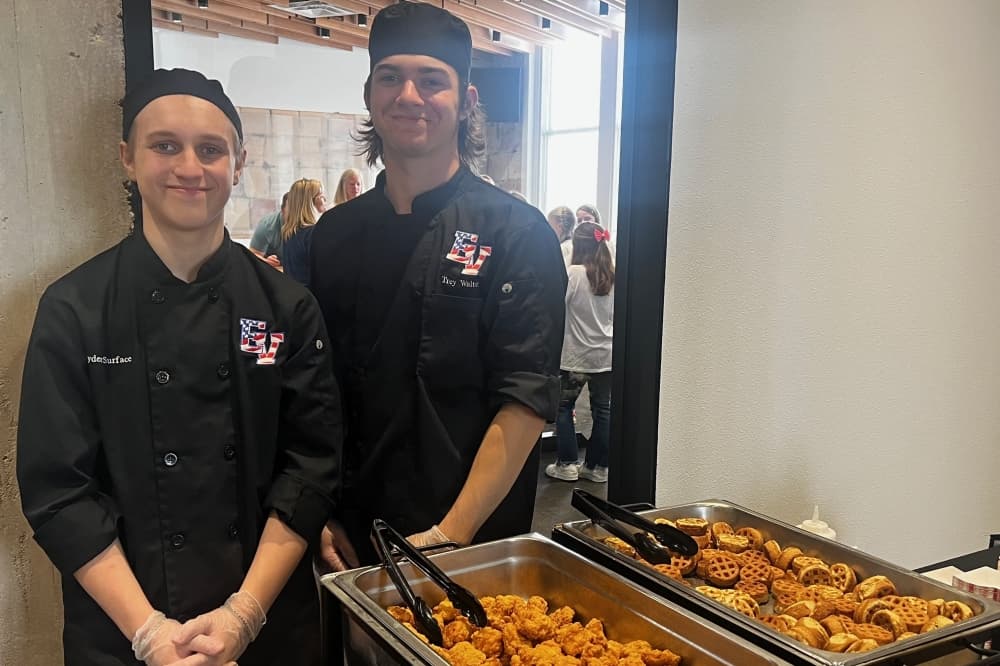 Students from the culinary program at Eastview High School, Trey Walter (left) and Jayden Surface, serve food to visitors at the state of the district. (Tekima Johnson/Community Impact)