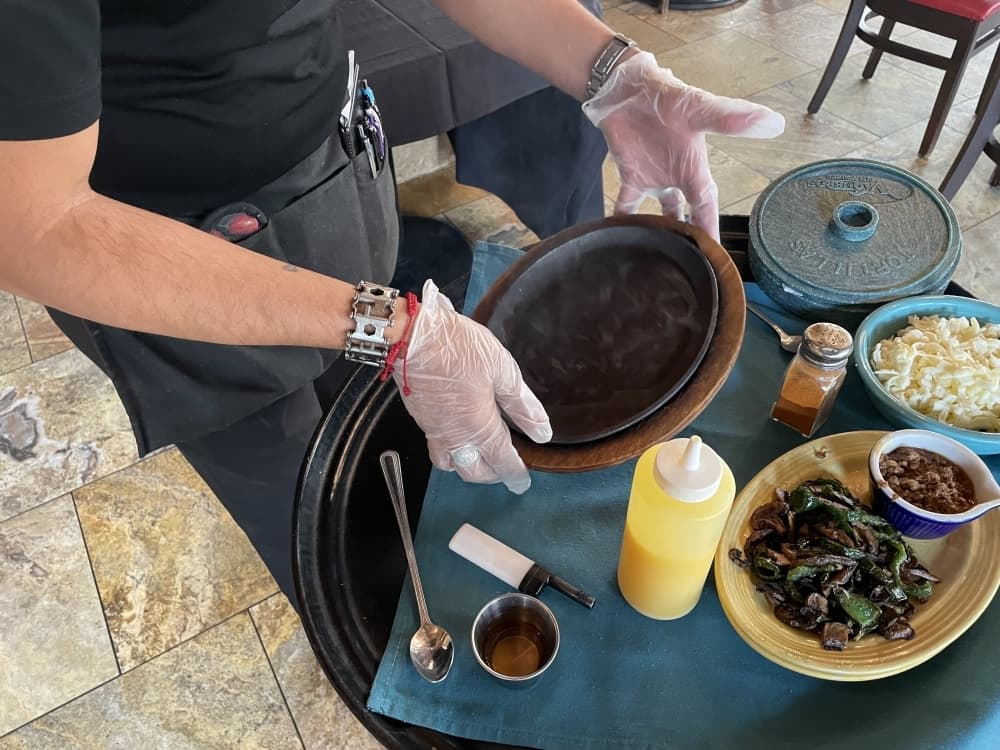 One of the popular dishes at Vaqueros Cafe & Cantina is called queso flameado, a flaming queso with cheese, chorizo, mushrooms and poblanos made tableside for customers. Step 1: Put butter on an already heated skillet-plate. (Taylor Cripe/Community Impact)