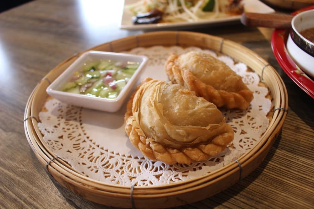 The chicken curry puff pastries ($6) are paired with a sweet vinaigrette with cucumber and red onion. (Jessica Shorten/Community Impact)