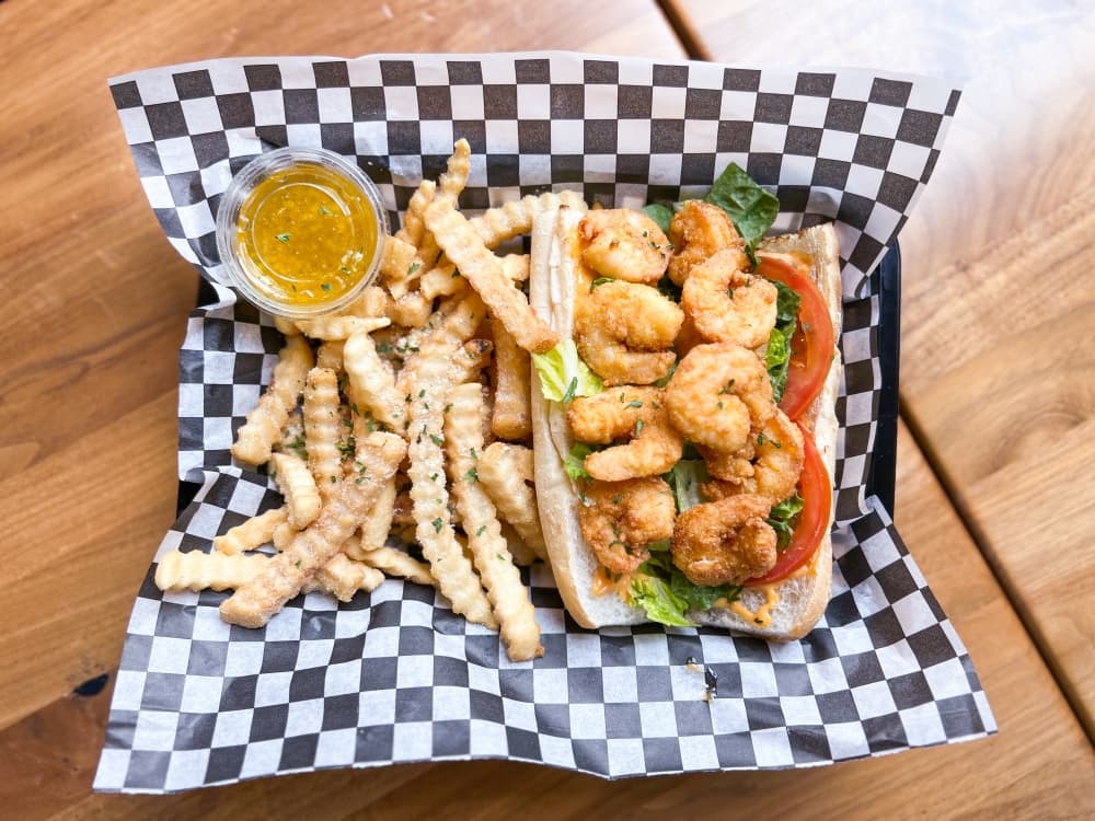 shrimp po'boy on french bread with french fries and sauce