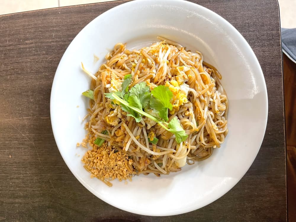 pad thai on white plate with green garnish