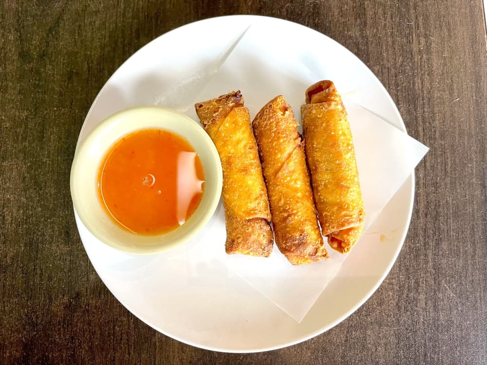 egg rolls on white plate with orange sweet and sour sauce 