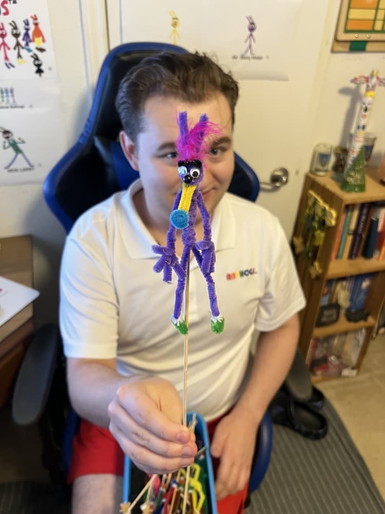 tristan holds purple creature made out of pipe cleaners