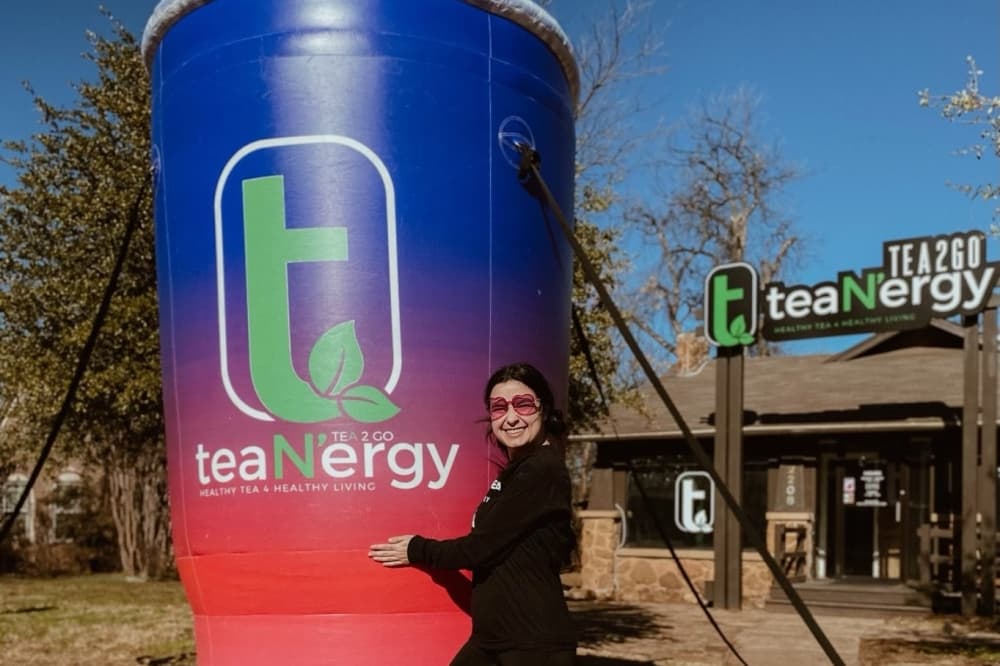 A woman standing with a large energy drink balloon