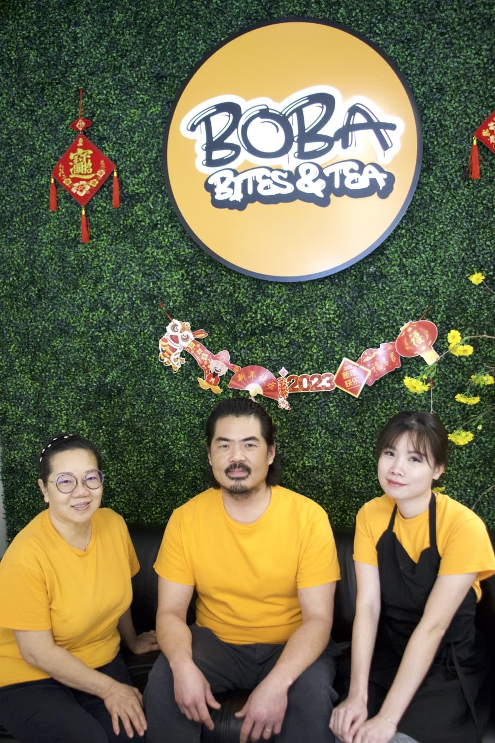 three people sitting in front of restaurant sign
