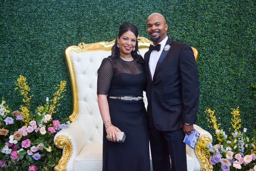 Maya and Datren Williams pose in front of a large white chair