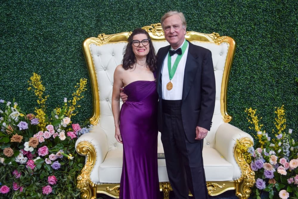 Pamela and Robert Heineman pose in front of a large white chair.