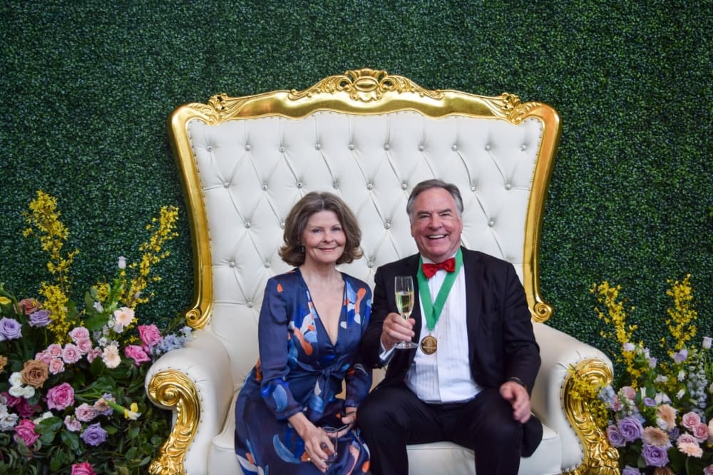 Diana and Bruce Tough pose sitting in a large white chair. 