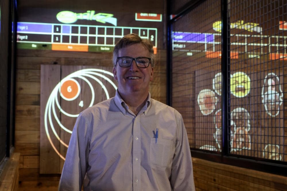 Neil Farren from Strikz Entertainment poses in front of axe throwing game