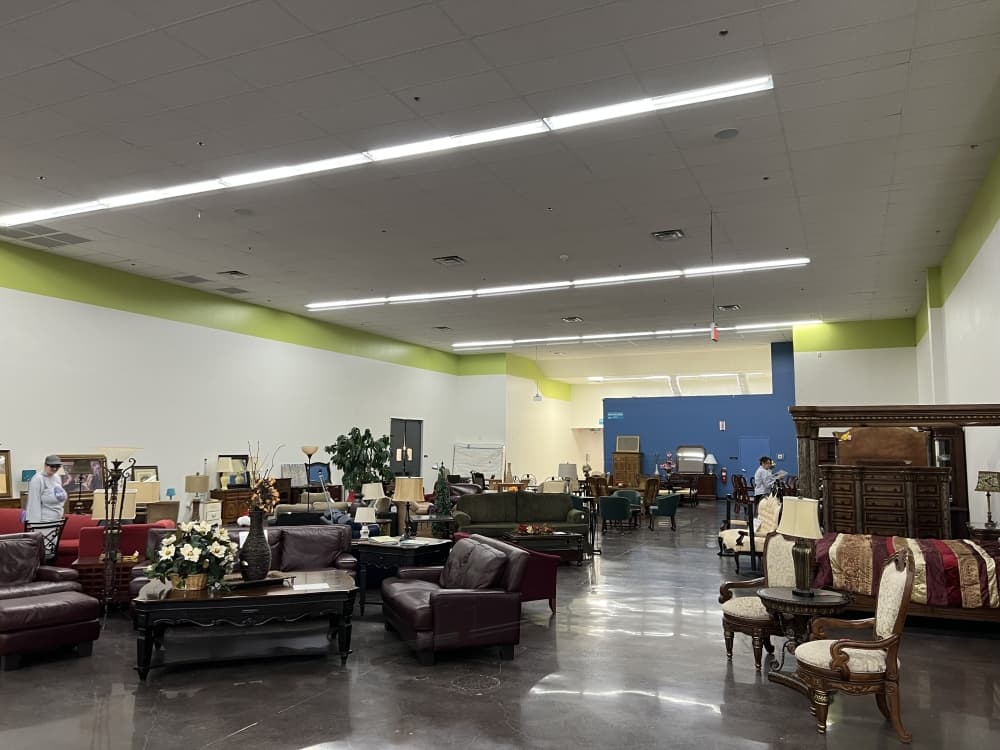 brown couches, tables and other furniture in an open storeroom 