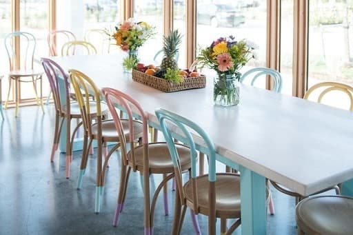Colorful pastel tipped chairs line a blue table at Melange Creperie