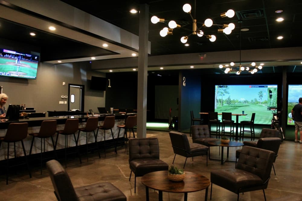 Interior of The Clubhouse Indoor Golf with tables and chairs