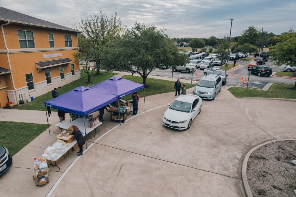 Vehicles line up for outdoor food pantry tent pickup
