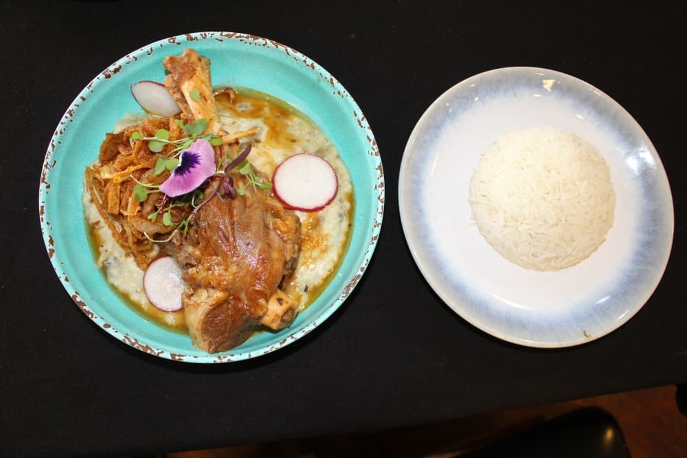 Lamb shank is served with mashed eggplant and rice.