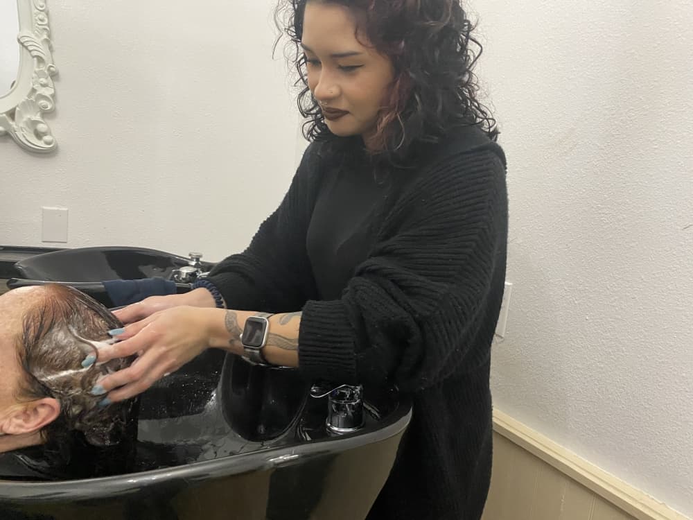 Level 1 employee xxx rinses a client's hair. 
