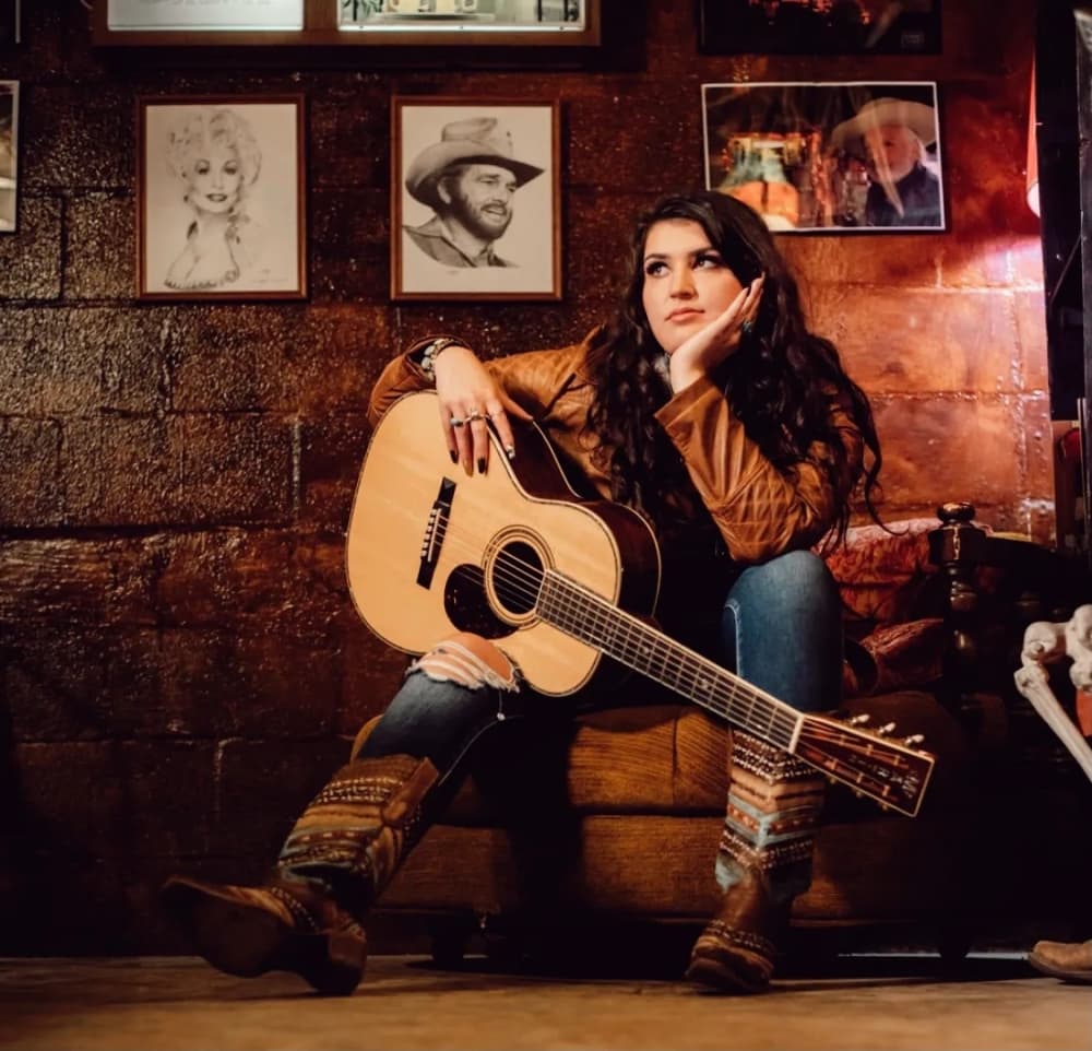 A country singer poses with a guitar.